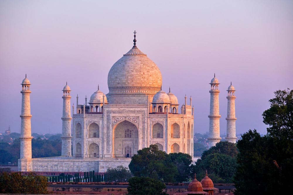 Taj Mahal i Agra vid soluppgång med ett varmt gyllene ljus som faller över det vita marmormausaleet